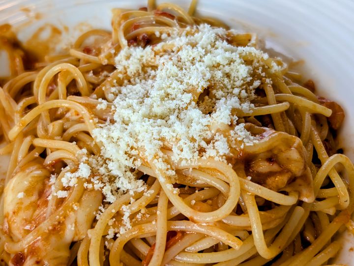 パスタに粉チーズをたっぷりかけている様子