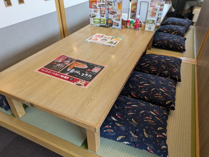 とんでんの座敷席 大きな座卓と魚柄の座布団が並ぶ小上がり