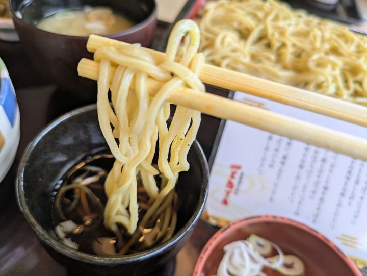 そばつゆにつけた柚子切りそばの麺を箸で持ち上げたところ