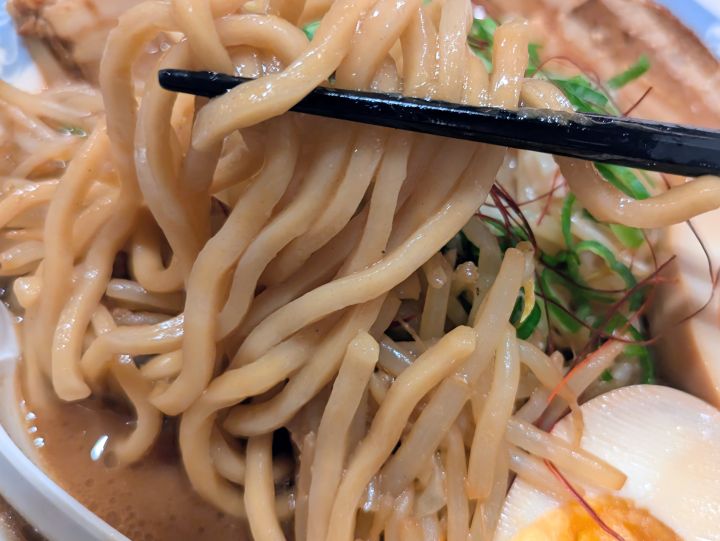 バーミヤン味噌バミ郎そばのやや太めの麺を箸で持ち上げたアップ